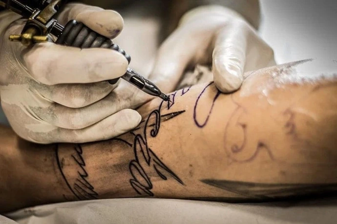 Machine à tatouer entre les mains d'un artiste